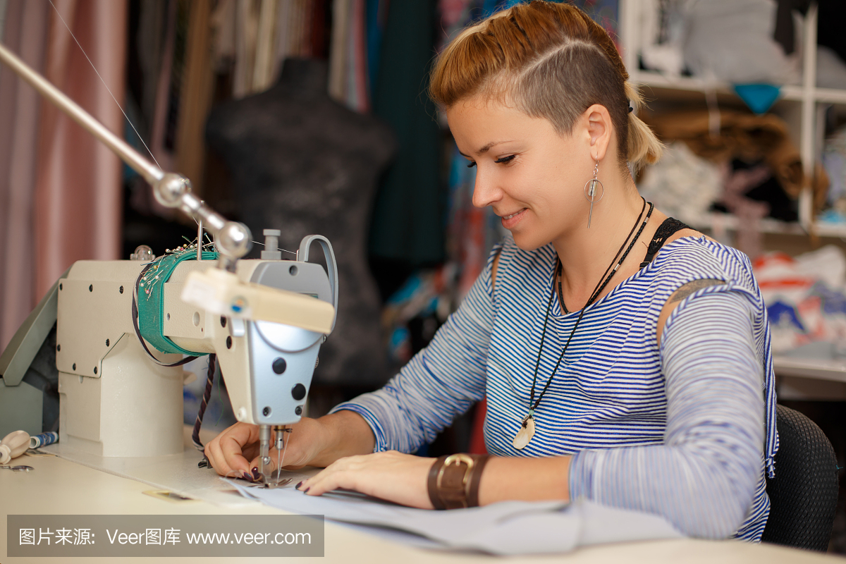 年轻的金发女裁缝在缝纫机上工作。服装制造业